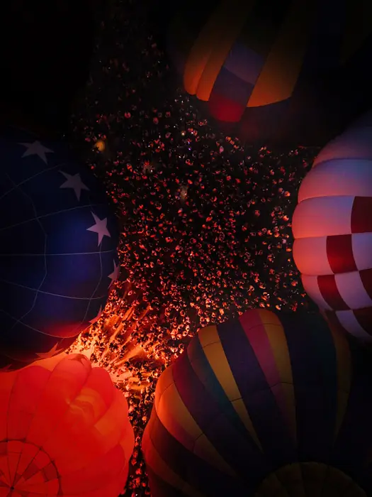 Overhead view of hot air balloon tops and the crowd forming patterns at night