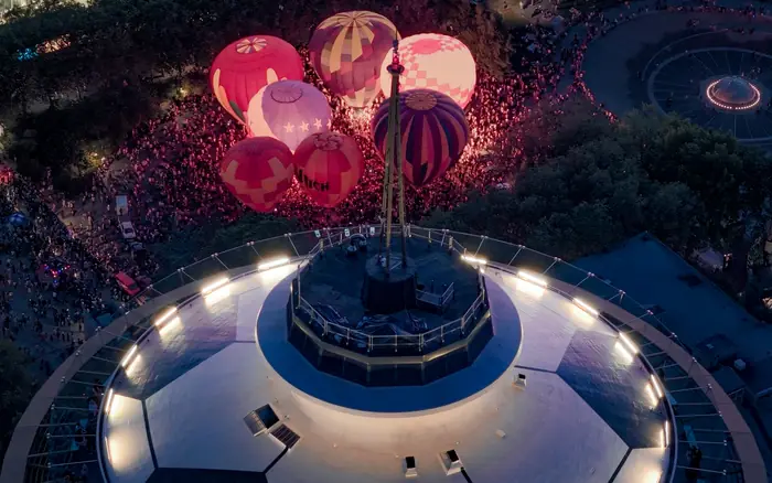 Glowing hot air balloons behind the illuminated top of the Space Needle