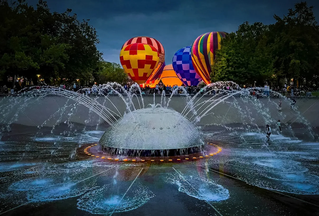 Hot air balloons glowing behind the International Fountain at Seattle Center